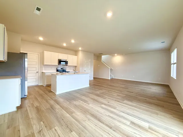 a view of kitchen with kitchen island a sink wooden floor and a refrigerator