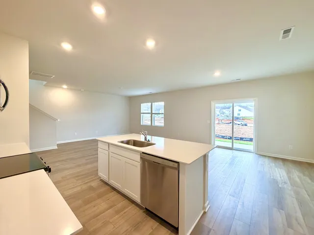 a kitchen with a sink stove and wooden floor