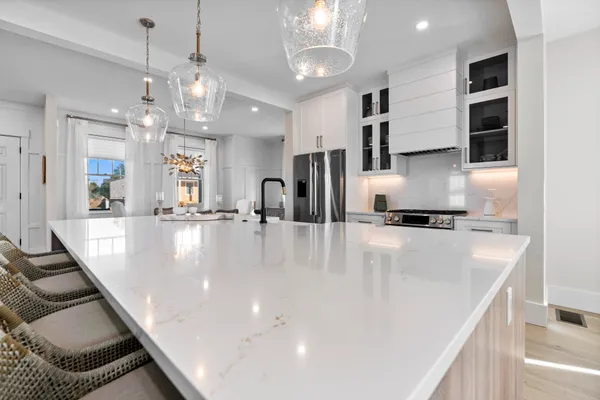 a large kitchen with stainless steel appliances a large counter top a stove and a chandelier