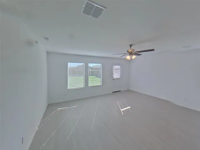 an empty room with windows and ceiling fan