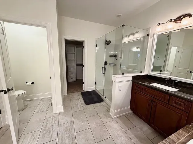 a large white bathroom with a sink a toilet a mirror and shower