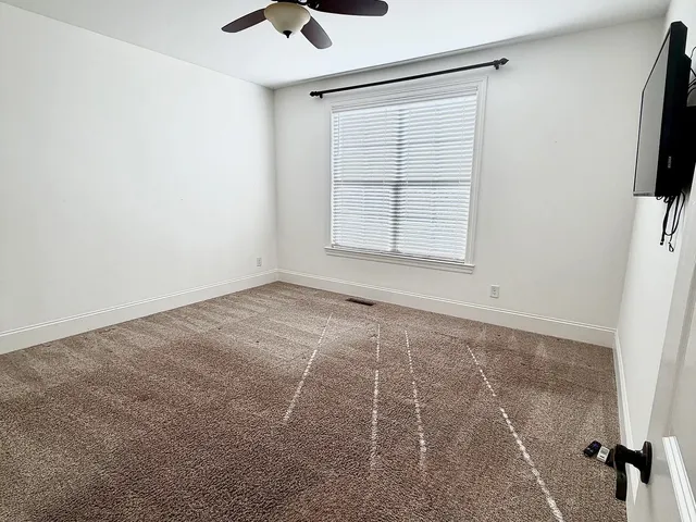 an empty room with windows and fan