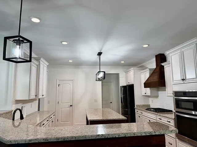 a kitchen with stainless steel appliances kitchen island granite countertop a sink and a stove top oven with granite countertops