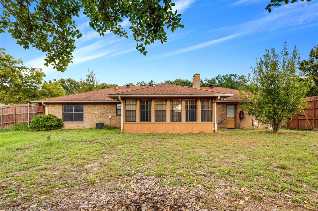 1609 Robin Street Mineola, TX 75773 - Photo 24 of 24 Rear exterior featuring a brick facade, a shingled roof, a sunroom with multiple windows, and a chimney