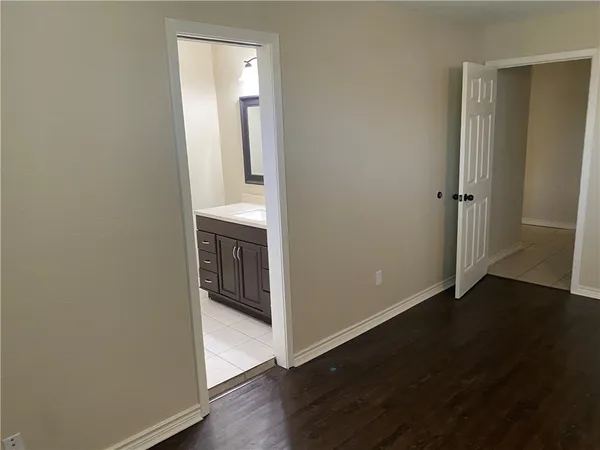 an empty room with wooden floor cabinet and door