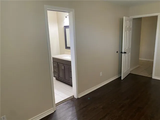 an empty room with wooden floor cabinet and door