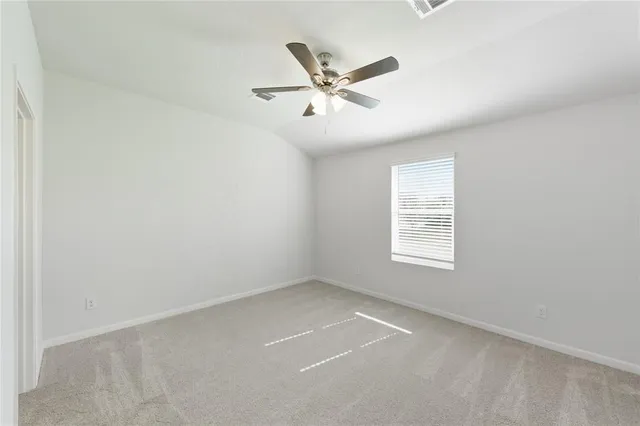 an empty room with window and ceiling fan