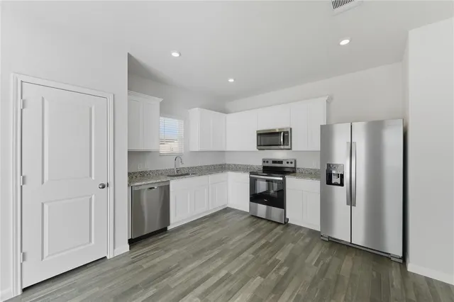 a kitchen with a refrigerator cabinets and wooden floor