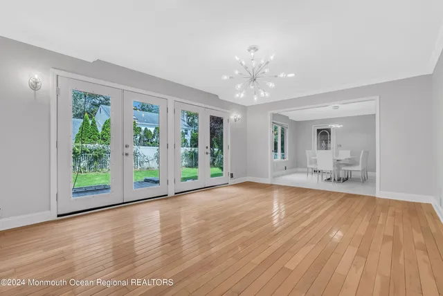 a view of an empty room with wooden floor and chandelier