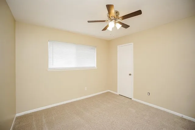 an empty room with a window and a ceiling fan