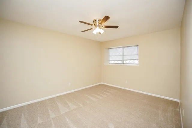 an empty room with a window and a fan