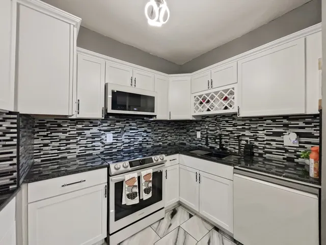 a kitchen with granite countertop white cabinets and black appliances