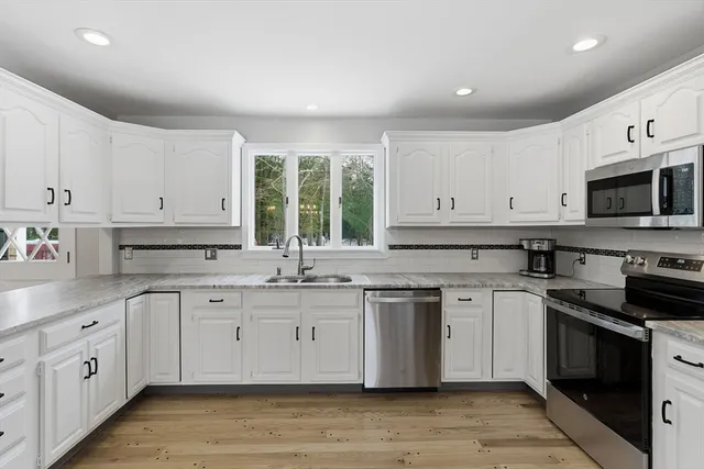 a kitchen with white cabinets stainless steel appliances and sink