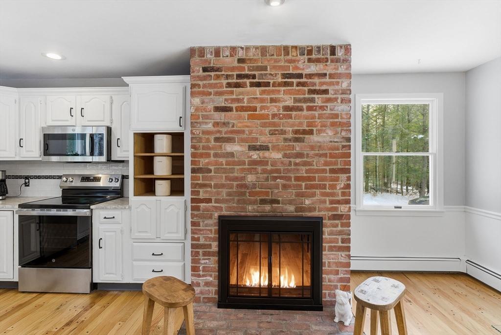 75 Barre Road Hubbardston, MA 01452 - Photo 9 of 42 a kitchen with a stove and a fireplace