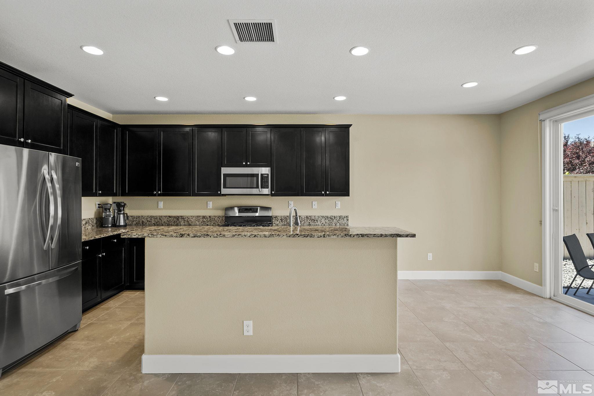 10819 Walnut Ridge Drive Reno, NV 89521 - Photo 4 of 22 a kitchen with kitchen island stainless steel appliances a sink a stove a microwave and a refrigerator