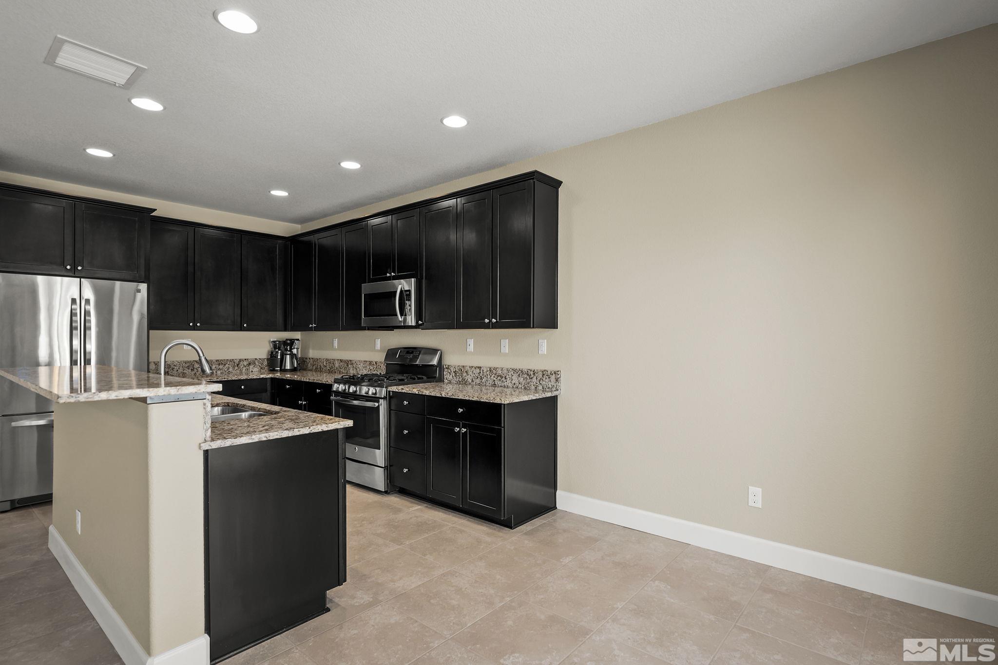 10819 Walnut Ridge Drive Reno, NV 89521 - Photo 5 of 22 a kitchen with stainless steel appliances granite countertop a stove a sink and a refrigerator