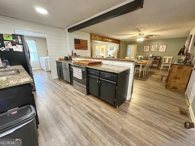a large kitchen with stainless steel appliances granite countertop a stove and a wooden floors