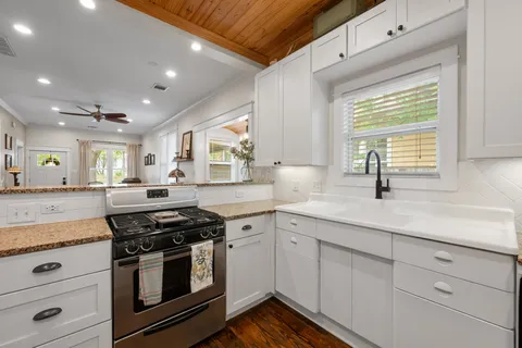 a kitchen with stainless steel appliances granite countertop white cabinets and a window