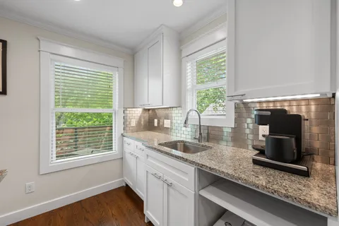 a kitchen with granite countertop a sink a counter appliances and a window