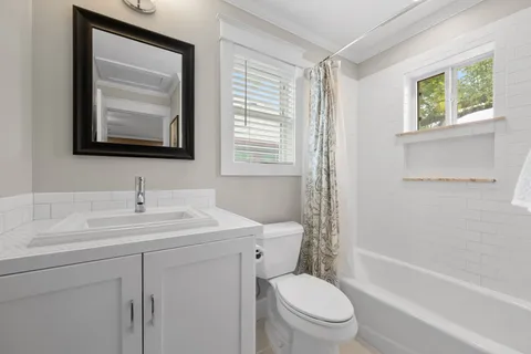 a bathroom with a toilet a sink a mirror and a bathtub