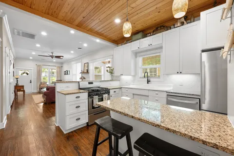 a large kitchen with granite countertop a large counter top appliances and cabinets