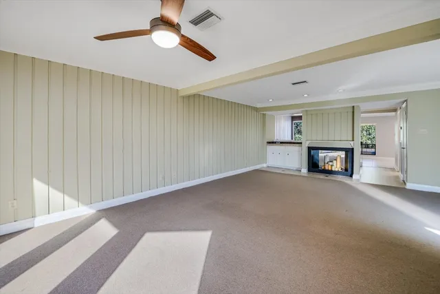 a livingroom with a fireplace a ceiling fan and a rug