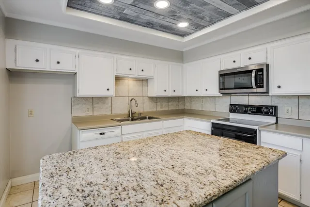 a kitchen with granite countertop a sink stove and cabinets