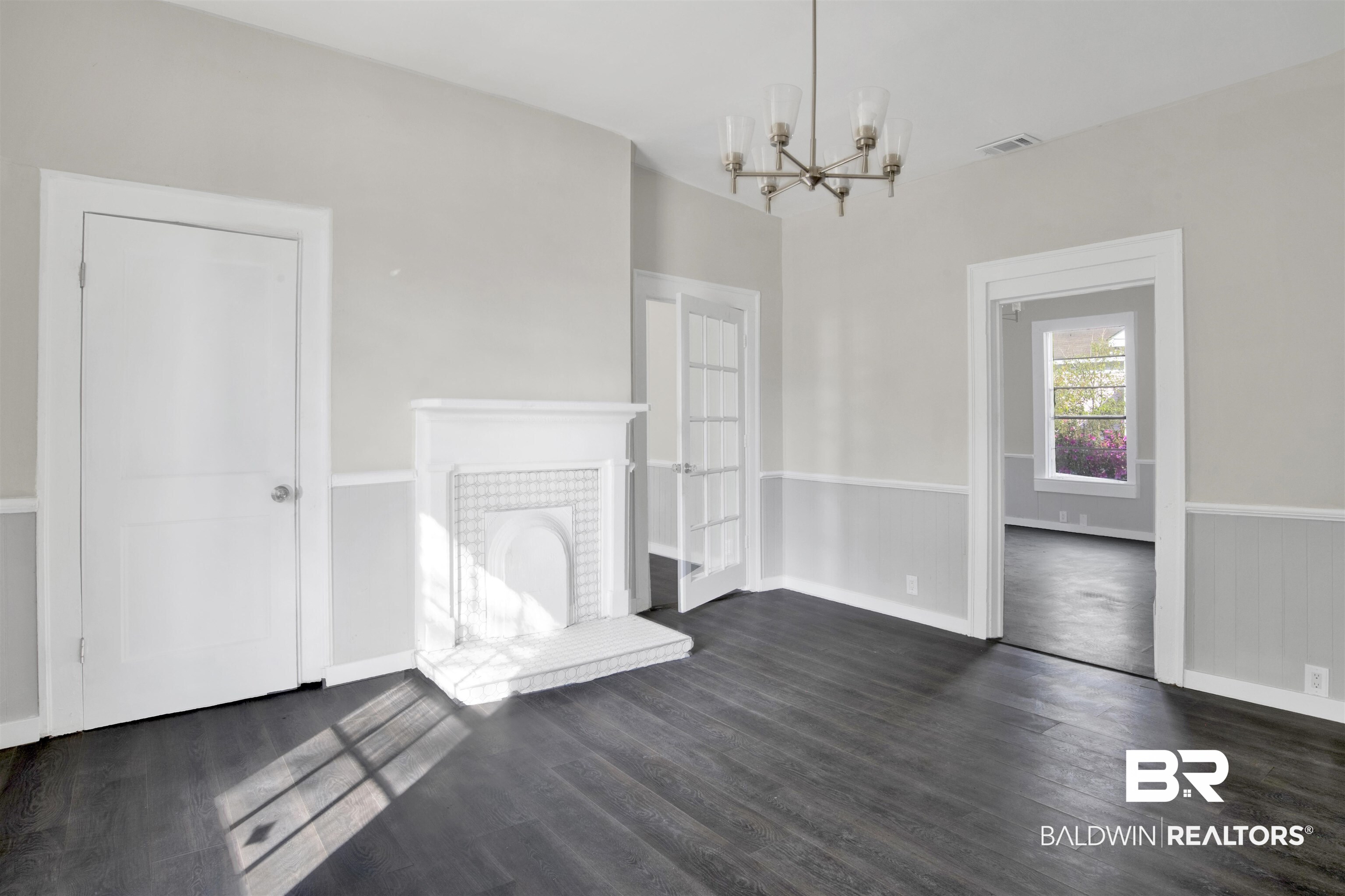 1063 Selma Street Mobile, AL 36604 - Photo 8 of 32 Unfurnished living room with a tiled fireplace, a chandelier, wainscoting, and dark wood-type flooring