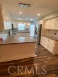 a view of a kitchen with kitchen island a sink wooden floor and a counter top space