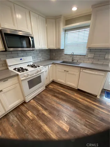 a kitchen with granite countertop a sink a stove and cabinets
