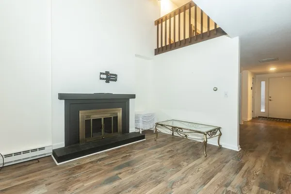 a living room with a fireplace furniture a ceiling fan and wooden floor