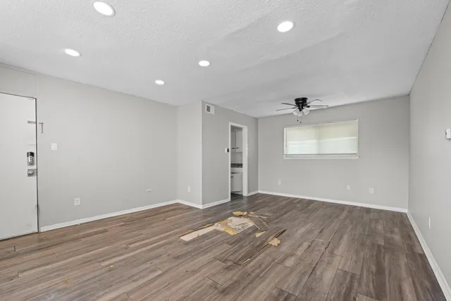 an empty room with wooden floor and windows