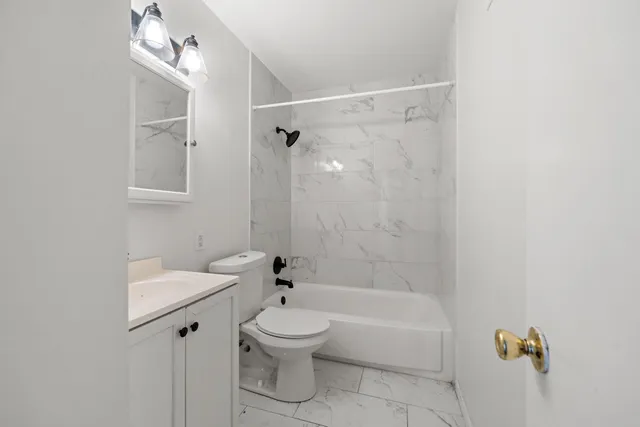 a bathroom with a bathtub shower sink vanity and a toilet