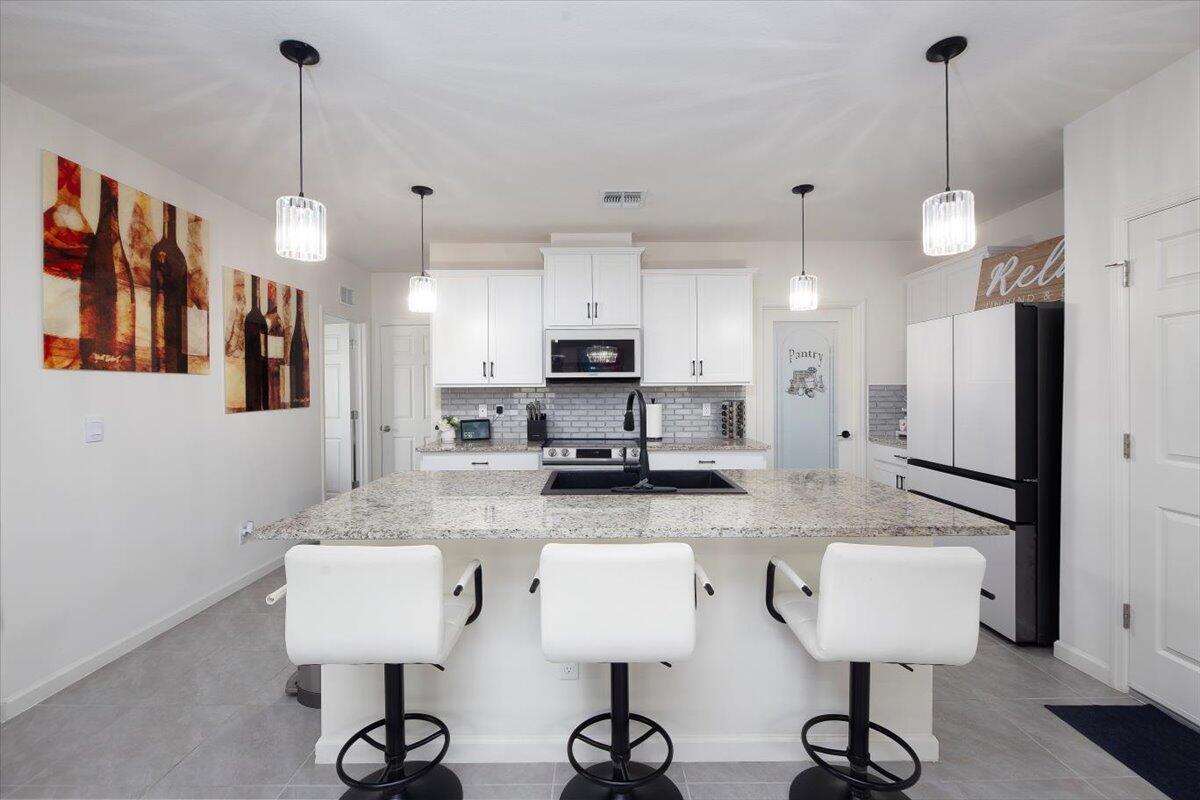 12314 Rimini Way Port St. Lucie, FL 34987 - Photo 9 of 49 a kitchen with stainless steel appliances kitchen island granite countertop a sink a refrigerator and a granite counter tops