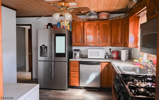 a kitchen with stainless steel appliances granite countertop a refrigerator a stove and a sink with wooden floor