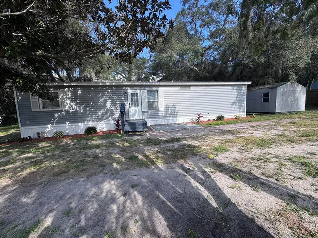 a backyard of a house with table and chairs a barbeque and a lots of trees