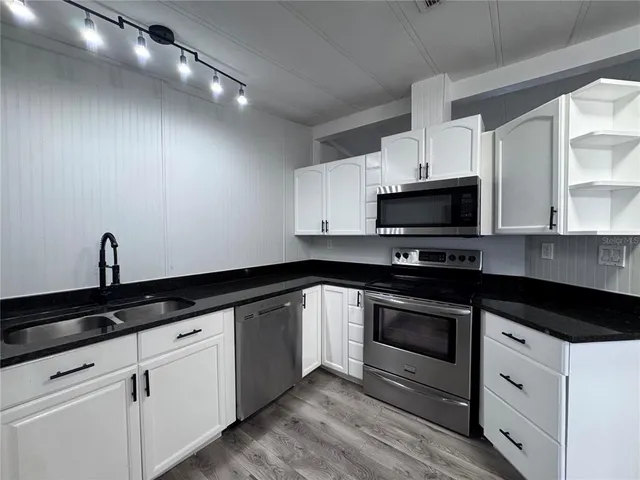 a kitchen with granite countertop white cabinets stainless steel appliances and a sink