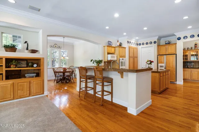 a view of a kitchen with kitchen island stainless steel appliances wooden floor dining table and chairs