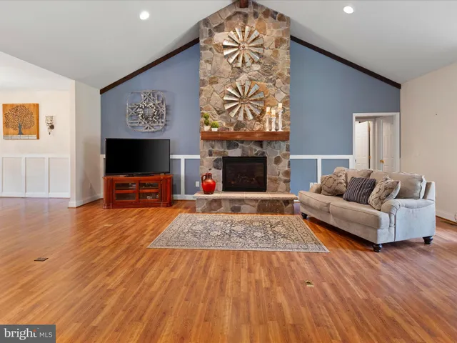 a kitchen with stainless steel appliances granite countertop a refrigerator a sink dishwasher a stove and a dining table with wooden floor