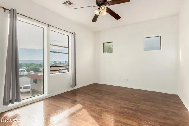 a view of empty room with wooden floor and fan