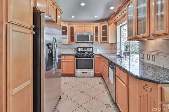 a kitchen with stainless steel appliances granite countertop a refrigerator a stove and a sink