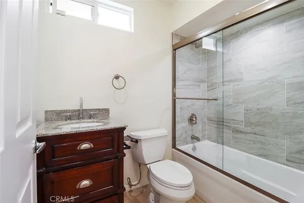 a bathroom with a granite countertop toilet a sink and a shower
