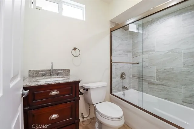 a bathroom with a granite countertop toilet a sink and a shower