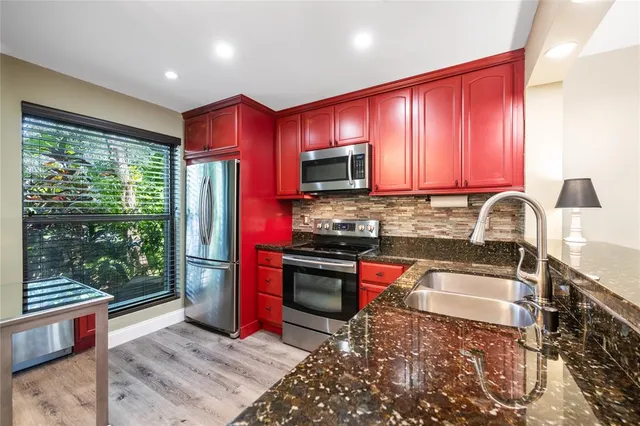 a kitchen with stainless steel appliances granite countertop a refrigerator a stove top oven a sink and dishwasher