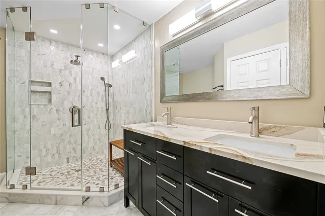 a bathroom with a granite countertop sink a mirror and shower