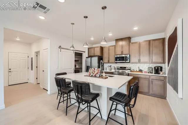 a kitchen with stainless steel appliances kitchen island granite countertop a dining table chairs and white cabinets