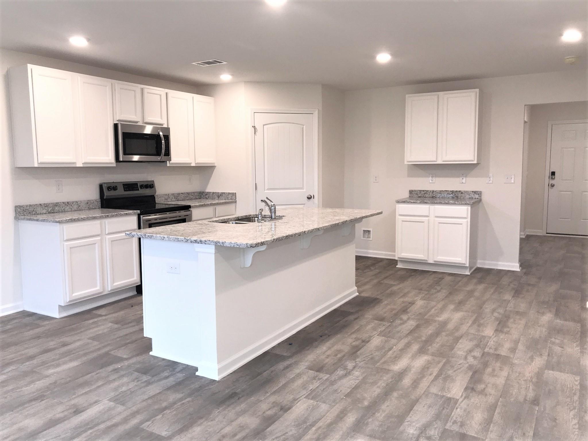 320 Flounder Street Crestview, FL 32539 - Photo 3 of 18 a kitchen with stainless steel appliances granite countertop a stove top oven a sink a refrigerator and white cabinets with wooden floor