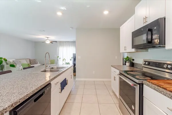 a kitchen with granite countertop white cabinets stainless steel appliances and a counter space