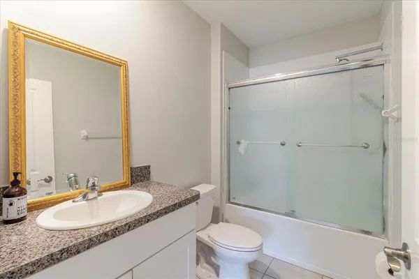 a bathroom with a granite countertop double vanity sink mirror and shower
