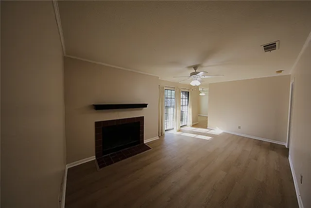 an empty room with wooden floor fireplace and windows